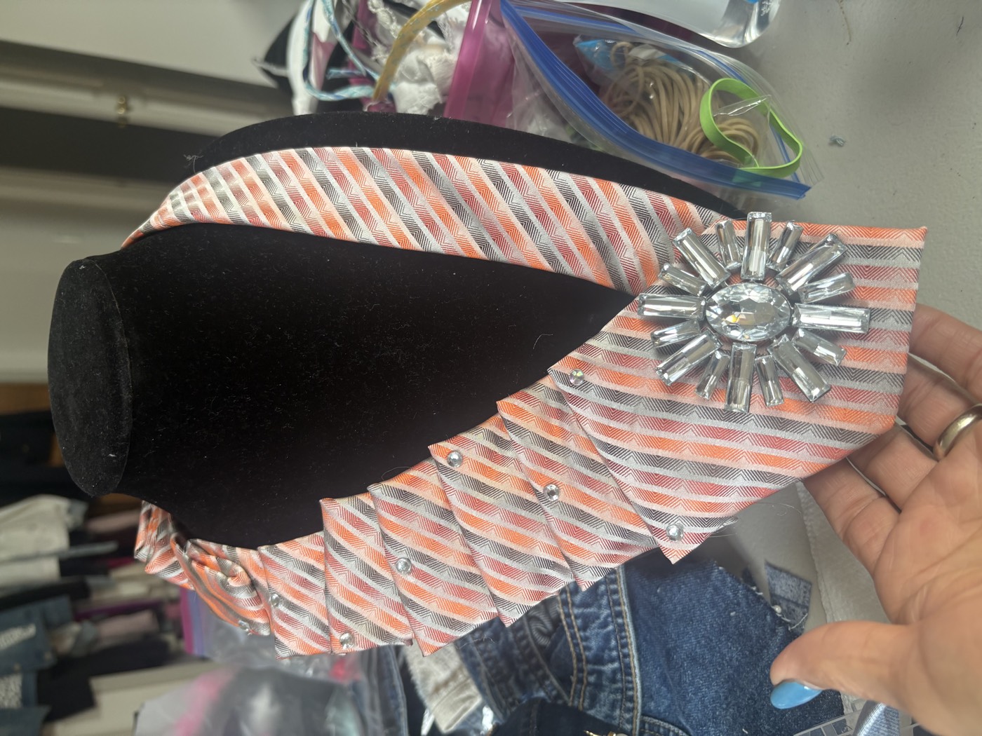 Coral and grey striped necktie, pleated on one side, with a large crystal starburst brooch.