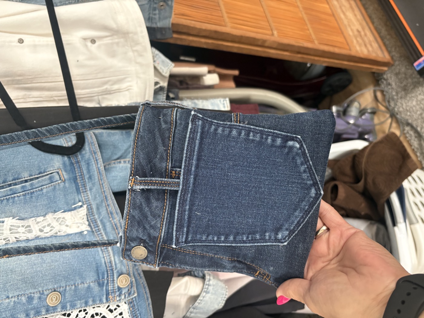 Small dark-wash denim crossbody bag built around a back pocket, with a long strap.